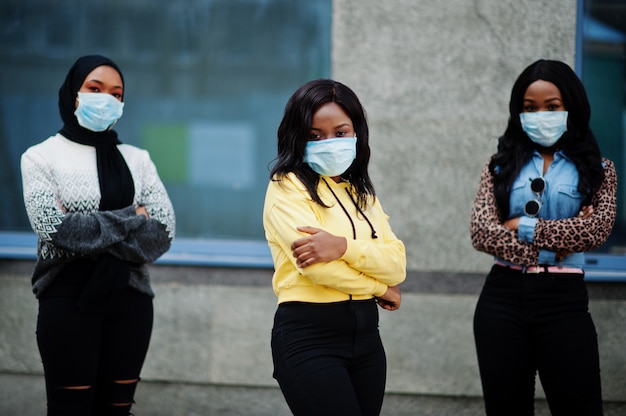 Group of three african american young volunteers wearing face mask outdoors. Coronavirus quarantine and global pandemic.