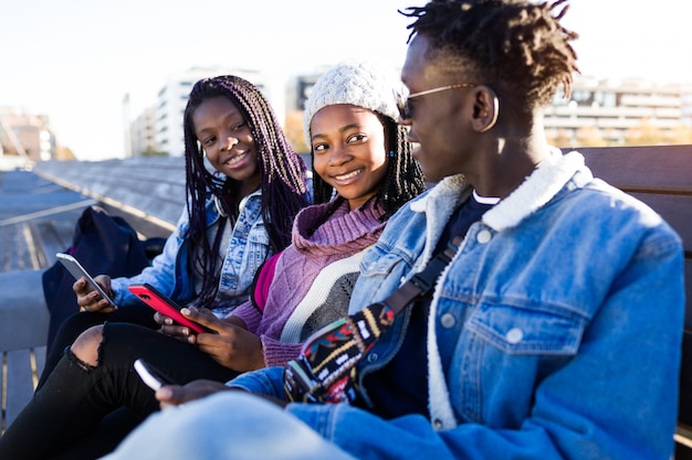 Group of three friends using mobile phone in the street.