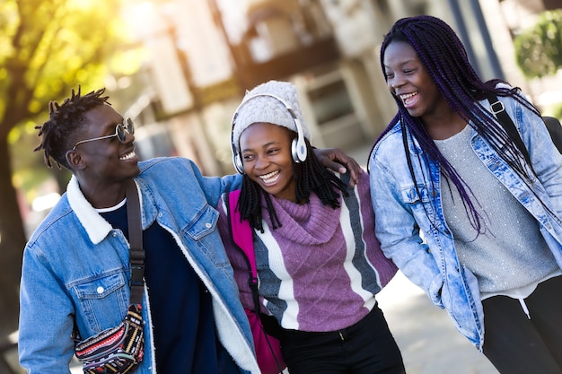 Photo group of three friends walking and laughing in the street.