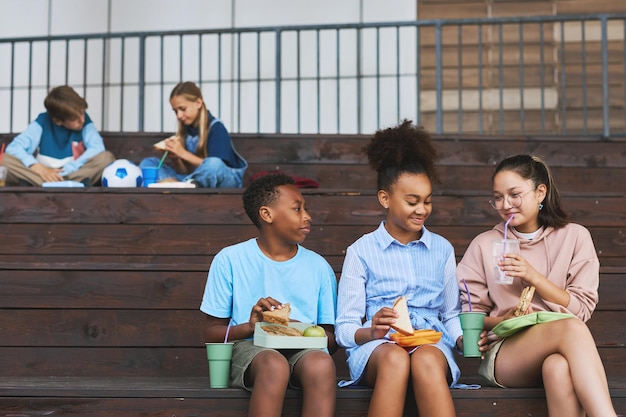 Group of three happy multicultural school friends having lunch