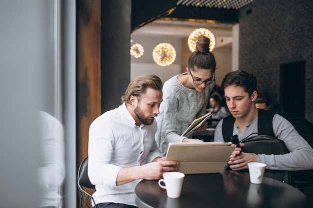 Group of three people working on a project on a tablet in a cafe