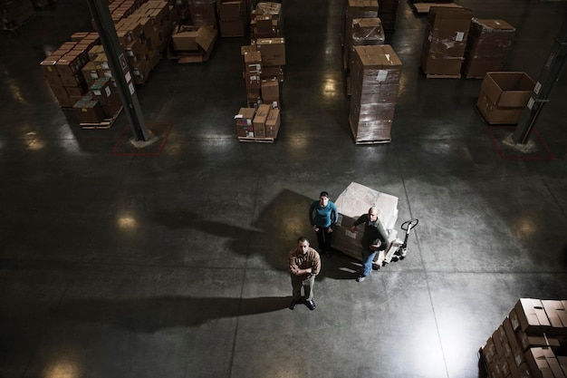 A group of three warehouse workers standing in the center of a distirbution warehouse