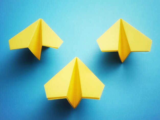Group of three yellow paper jets on blue background