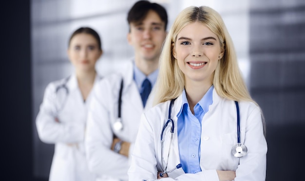 Group of three young doctors standing as a team with arms crossed in modern clinic and ready to help patients. Medicine concept.