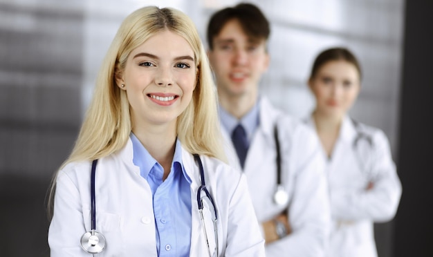 Group of three young doctors standing as a team with arms crossed in modern clinic and ready to help patients. Medicine concept.