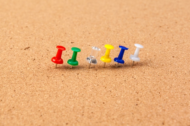 Group of thumbtacks pinned on corkboard