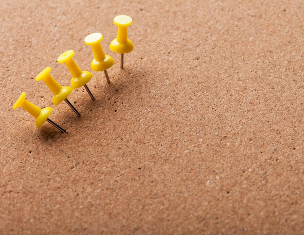 Group of thumbtacks pinned on corkboard