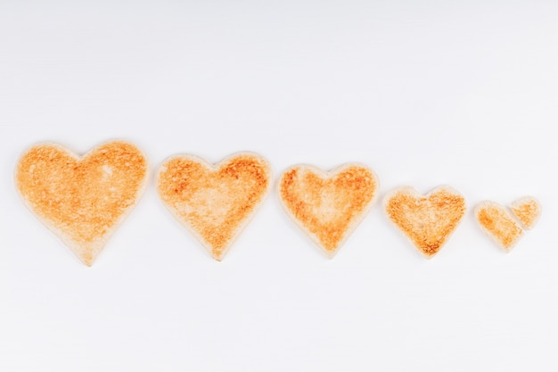 Gruppo di cuori di pane tostato con un cuore spezzato insieme su sfondo bianco