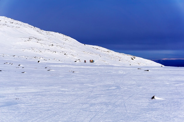 Group of tourists away in the mountainous arctic landscape under a bright blue sky