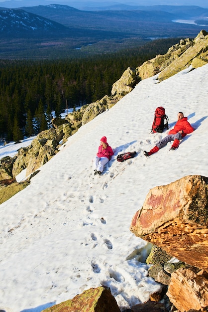 A group of tourists consisting of a girl and a guy lying on snegu on top of the mountain