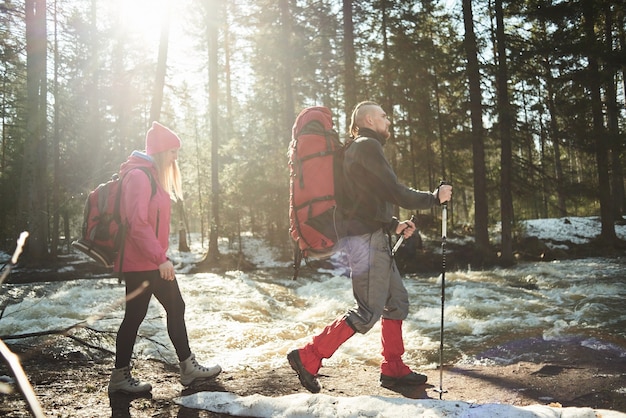 A group of tourists consisting of guys and girls going in the woods along the river