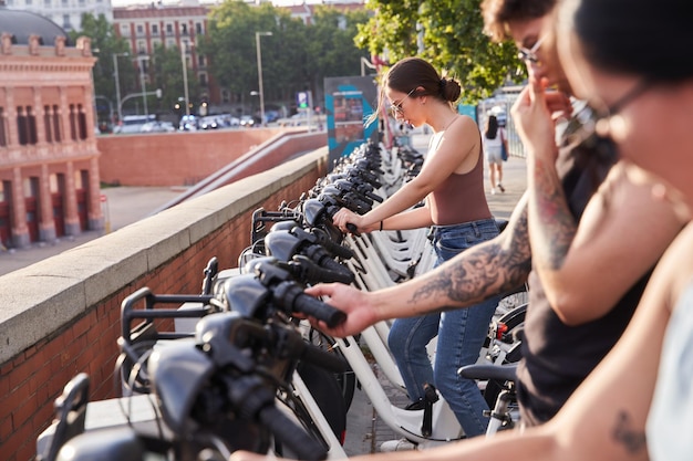 Group of tourists renting a bicycle with the mobile phone to visit the city Concept of city life