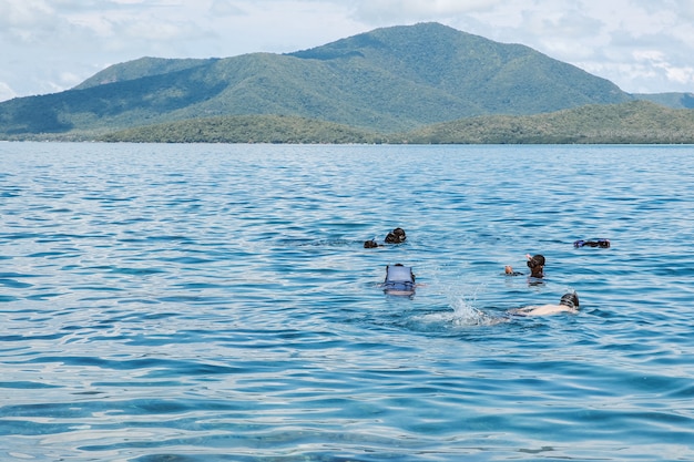 카리문 자와(Karimun Jawa)의 녹색 산을 바라보며 바다에서 수영과 스노클링을 하는 관광객 그룹