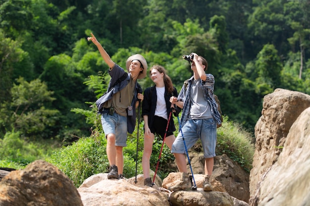 川と山のトレイルを歩くバックパックを持つ観光客のグループ
