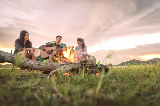 キャンプ場でピクニックをして音楽を一緒に演奏する旅行者のグループ。