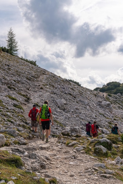 バックパックを背負った旅行者のグループが山の石の道を歩いている 下の山を登っている