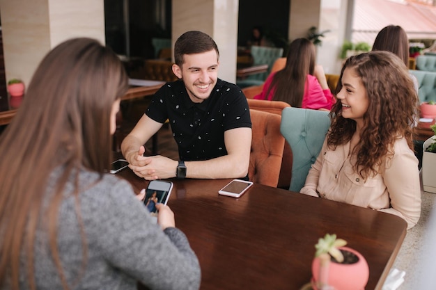 Group of tree friends on terrace Yound people meeting in cafe Friends sitting in cafe together Meeting