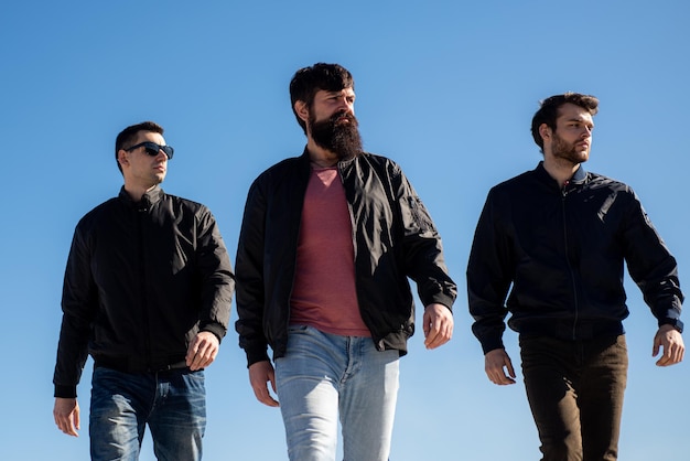 Group of trendy young people walking on street. Fashion men. Vogue men.