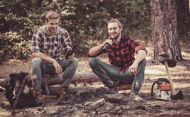 Group of two male friends camping with marshmallows over a camp\
fire summer vacation forest weekend