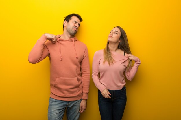 Group of two people on yellow background with tired and sick expression