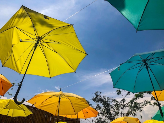 A group of umbrellas are hanging in the air and one of them is yellow.