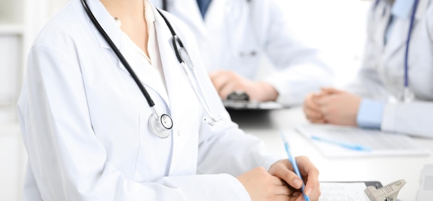 Group of unknown doctors discussing problems to stop coronavirus pandemic while sitting at meeting in clinic, close-up . Medicine concept.