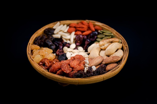 Group of various types of dried fruits and dried on a bamboo tray on black background