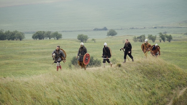 Foto gruppo di vichinghi con scudi che camminano in avanti sul prato