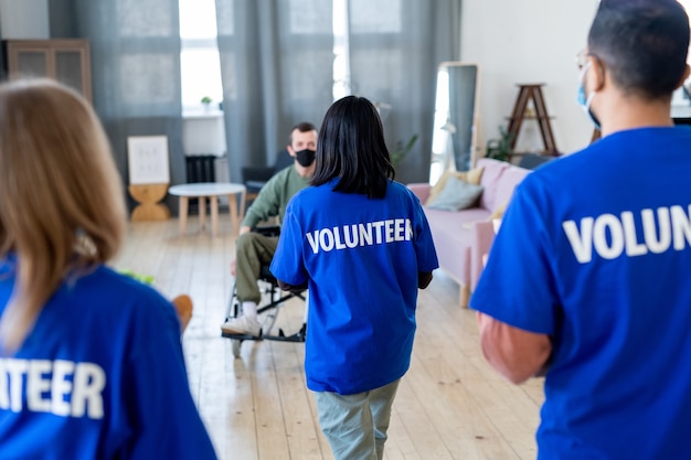 a group of volunteers moving towards young disable man in a room