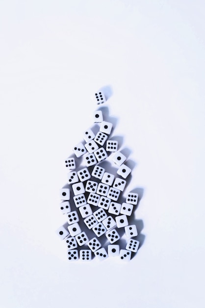 Group of white dices stacked on a white background in the shape of a Christmas tree.