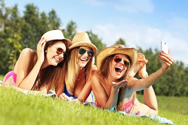 a group of women in bikin taking selfie outdoors