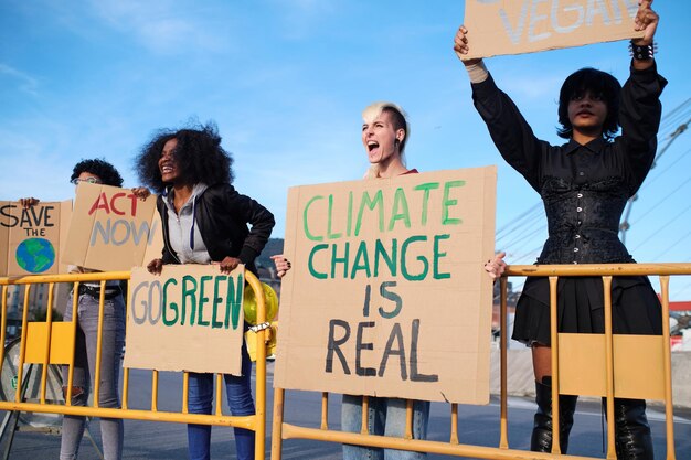 A group of women behind fences protesting and shouting against\
climate change with placards.