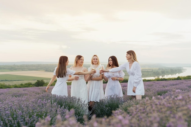 A group of women in white dresses stand in a lavender field