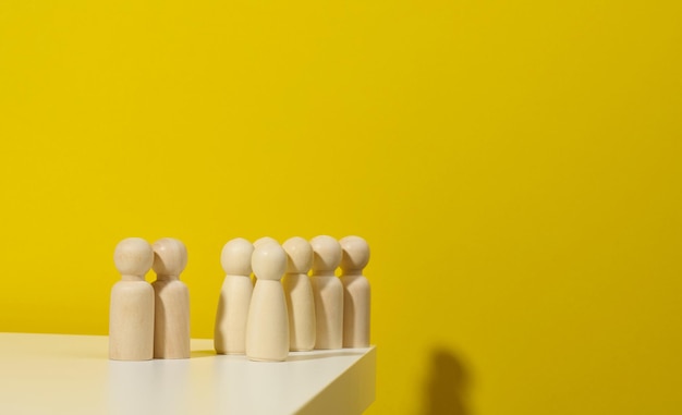 A group of wooden figurines on a yellow background the concept of a strong leader manipulation of the masses