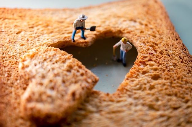 group of worker miniature fixing a burned sliced toasted bread with heart shape