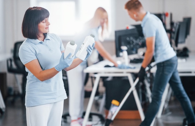 Photo group of workers clean modern office together at daytime