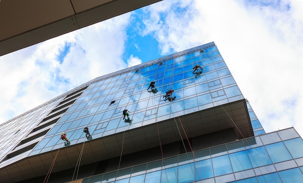 Group of workers cleaning windows service on high rise building\
work on the heights industrial mountaineering