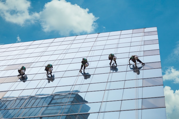 Gruppo di lavoratori che puliscono il servizio di finestre su un alto edificio