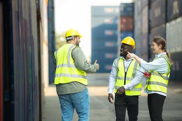 Group of workers in a container storage yard greeting each other during breaks in front of container