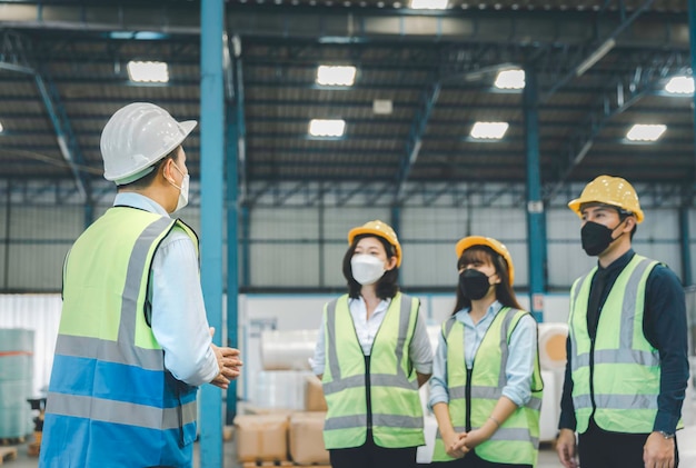 Gruppo di personale di lavoro in maschera medica facciale con riunione di sicurezza in fabbrica, concetto di sicurezza e salute sul lavoro