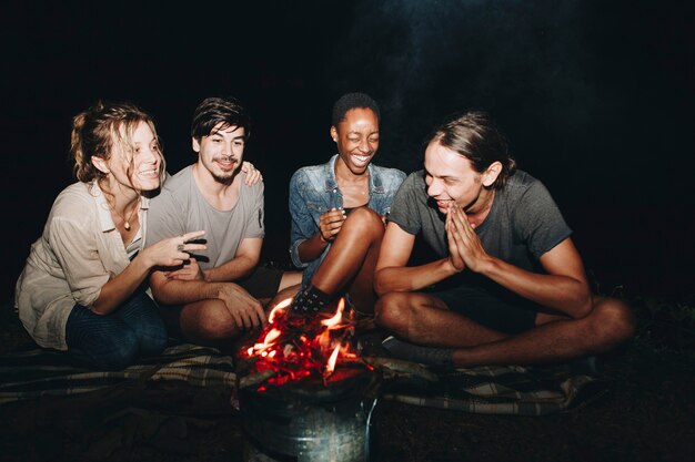 Group of young adult friends sitting around the bonfire