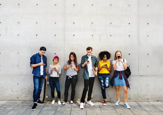 Group of young adults outdoors using smartphones together and chilling