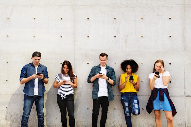 Group of young adults outdoors using smartphones together 