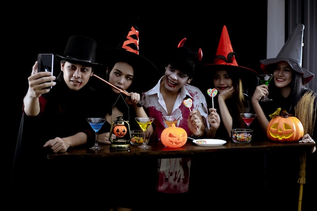 Group young Asian in costume celebrate Halloween party and selfie on black background. Gang of teen Asian in cosplay Halloween. Costume ghost, evil of group teen Thai with fun.