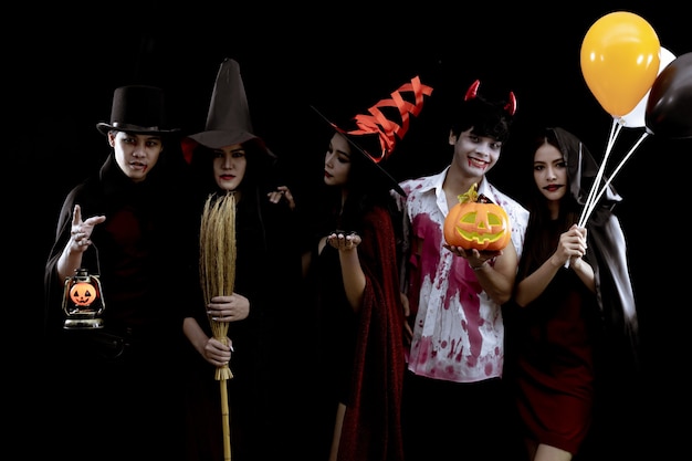 Group young Asian in costume Halloween party on black wall with concept for Halloween fashion festival . Gang of teen Asian in cosplay Halloween. Costume ghost, evil of group teen Thai.