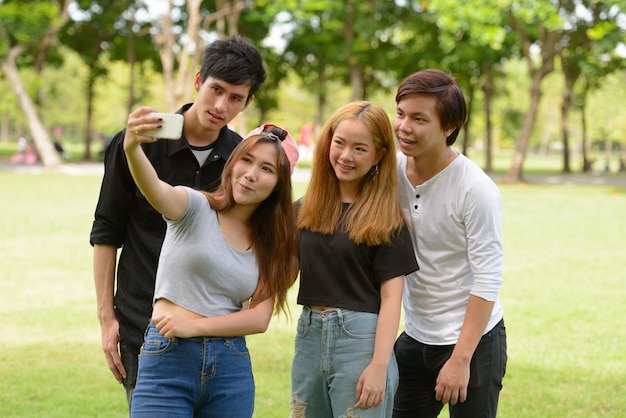 Group of young Asian friends hanging out and relaxing together at the park outdoors