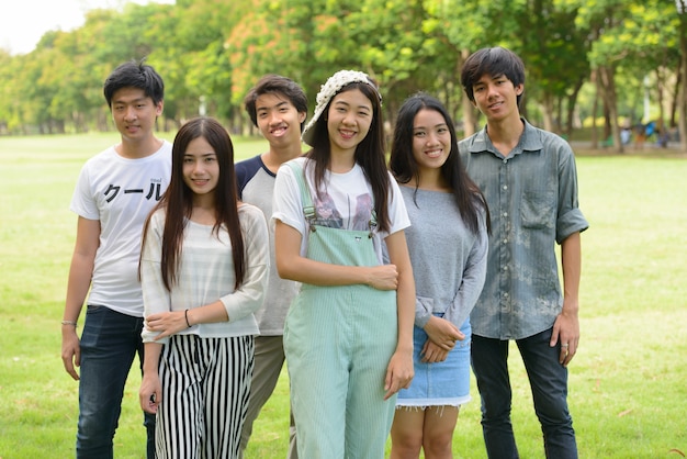 Group of young Asian friends hanging out and relaxing together at the park outdoors