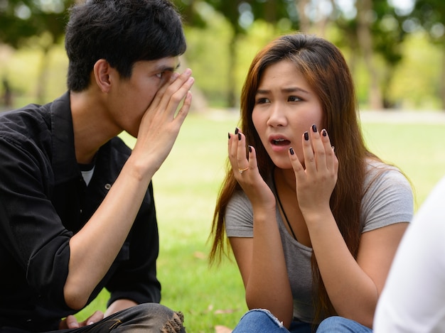 Group of young Asian friends hanging out and relaxing together at the park outdoors