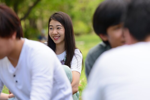 Группа молодых азиатских друзей, отдыхающих вместе в парке на открытом воздухе