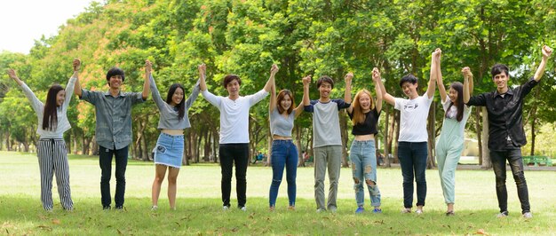 屋外の公園で一緒にぶらぶらしてリラックスしている若いアジアの友人のグループ